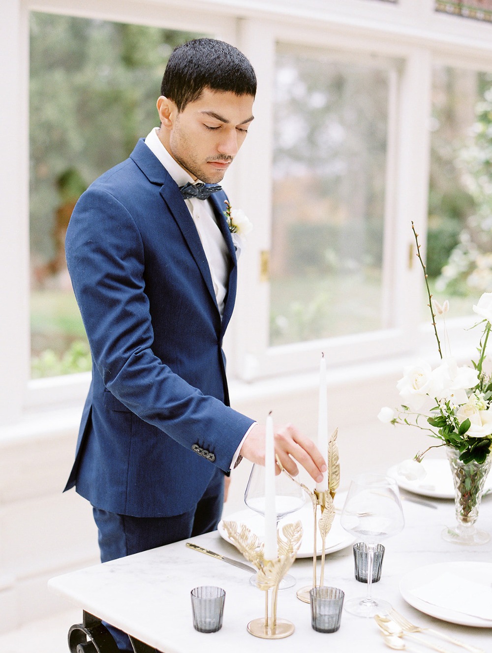 Groom arranging candles on a beautifully set wedding reception table