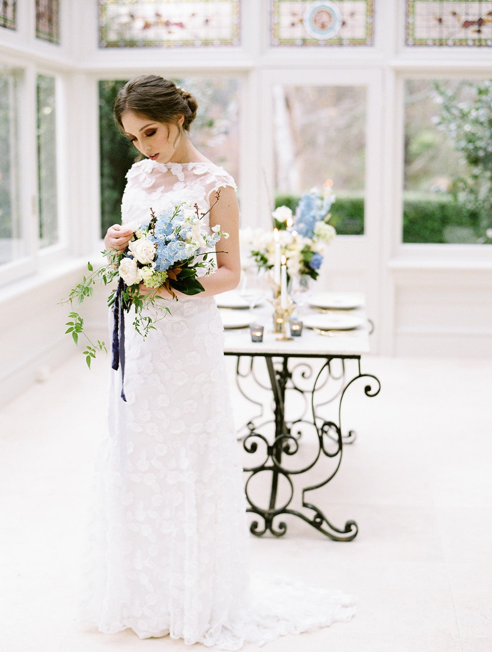 Elegant bride in white dress holding a beautiful bouquet in a light room