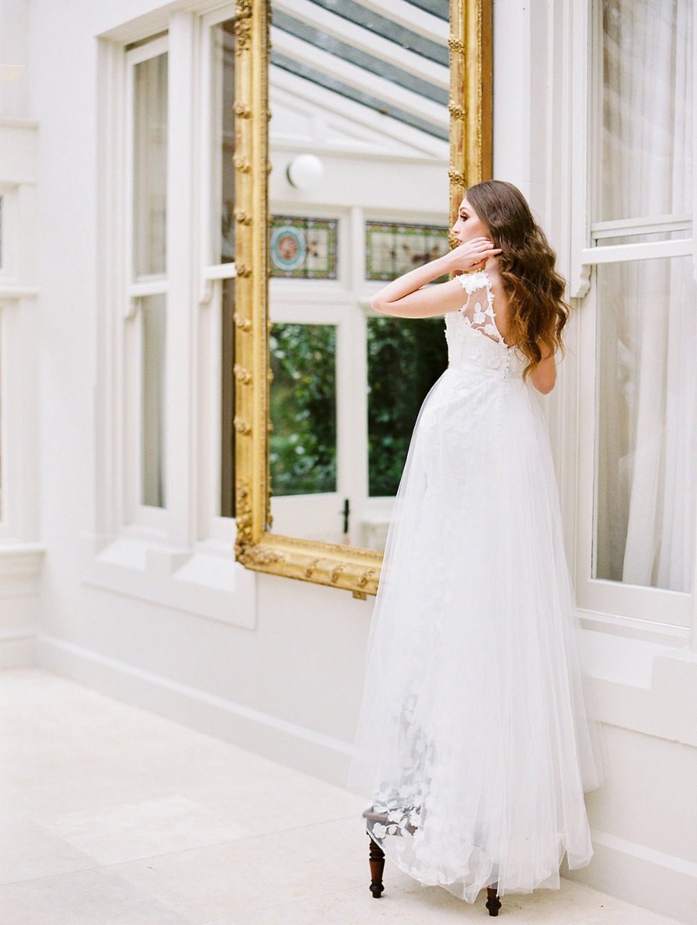 Bride in elegant dress looking at mirror, before wedding day