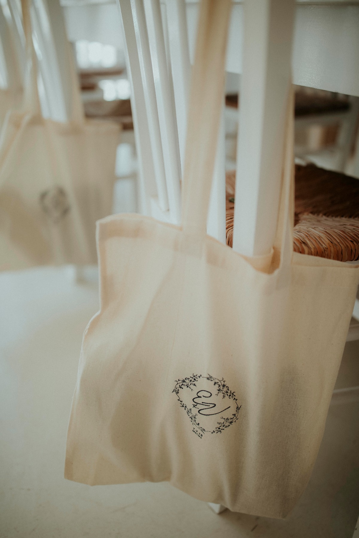 Elegant beige tote bags with floral letter E design on chairs