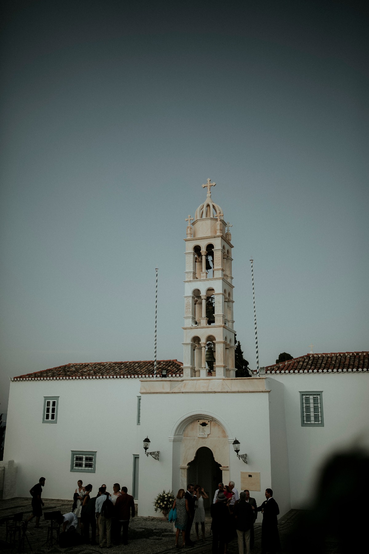 White church with bell tower on a sunny day with people gathered