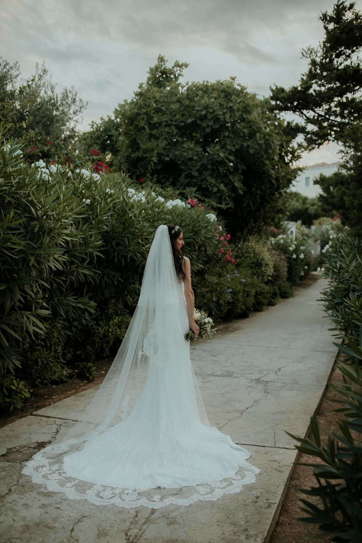 Bride in white wedding dress and long veil in garden