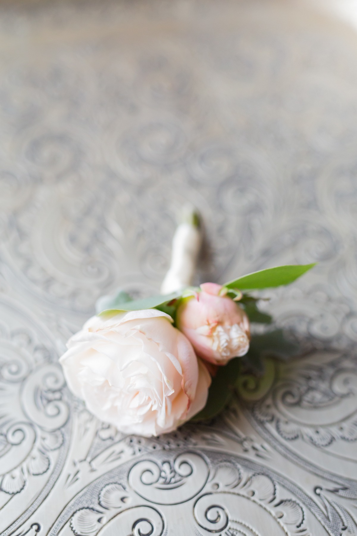 Elegant boutonniere with soft pink roses on ornate surface