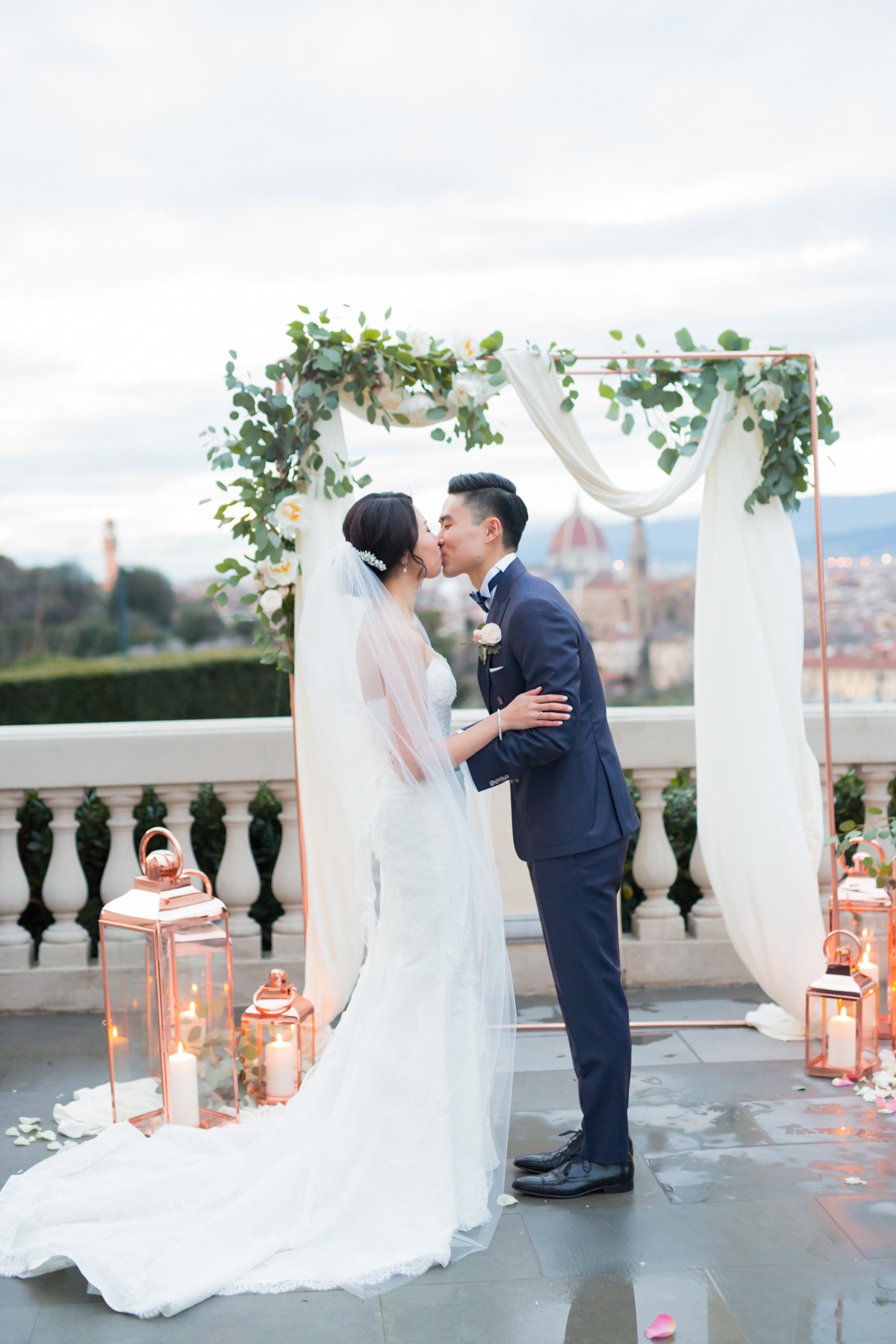 Couple kissing at their wedding ceremony with city backdrop