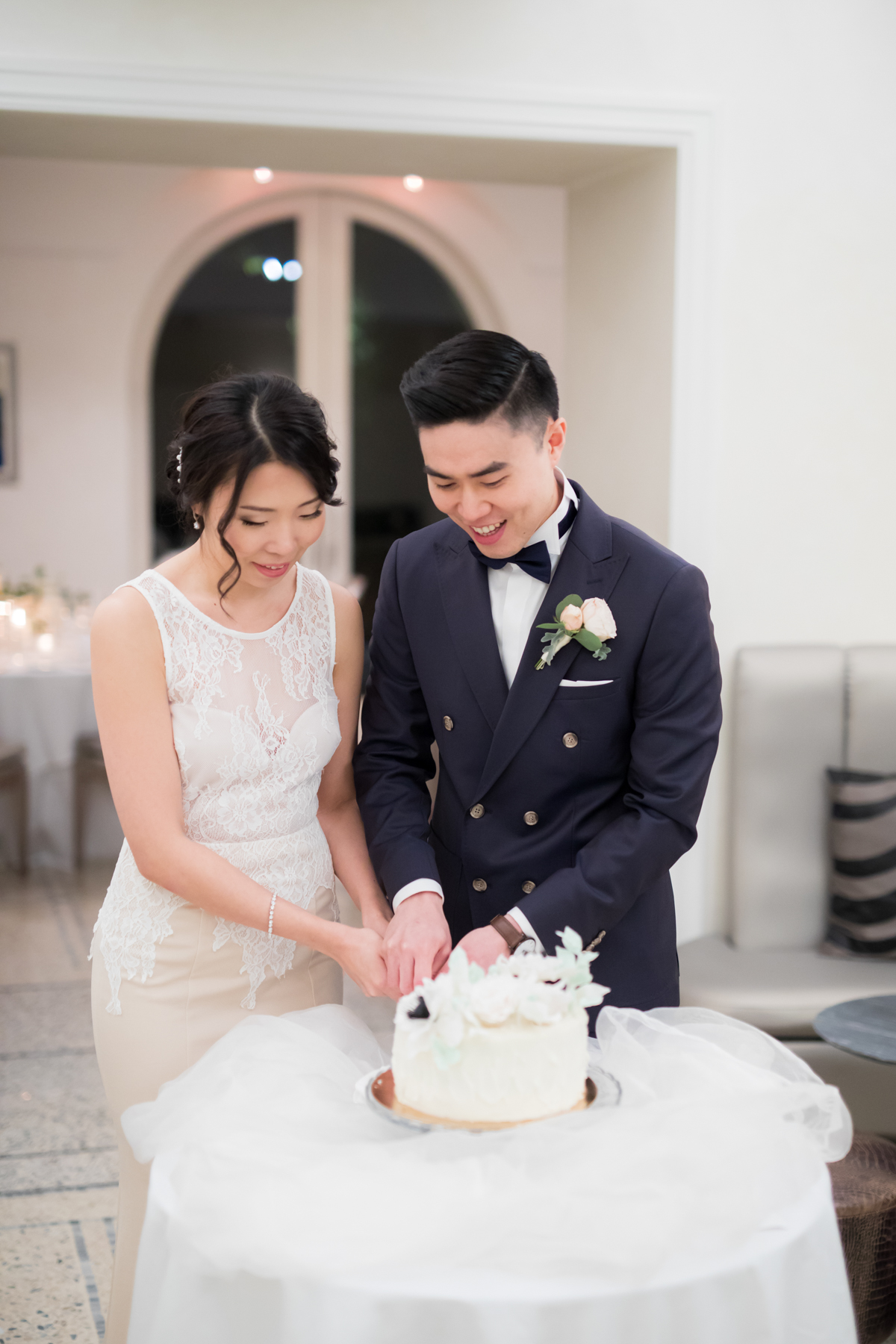Newlyweds cutting their wedding cake with smiles, a joyful moment
