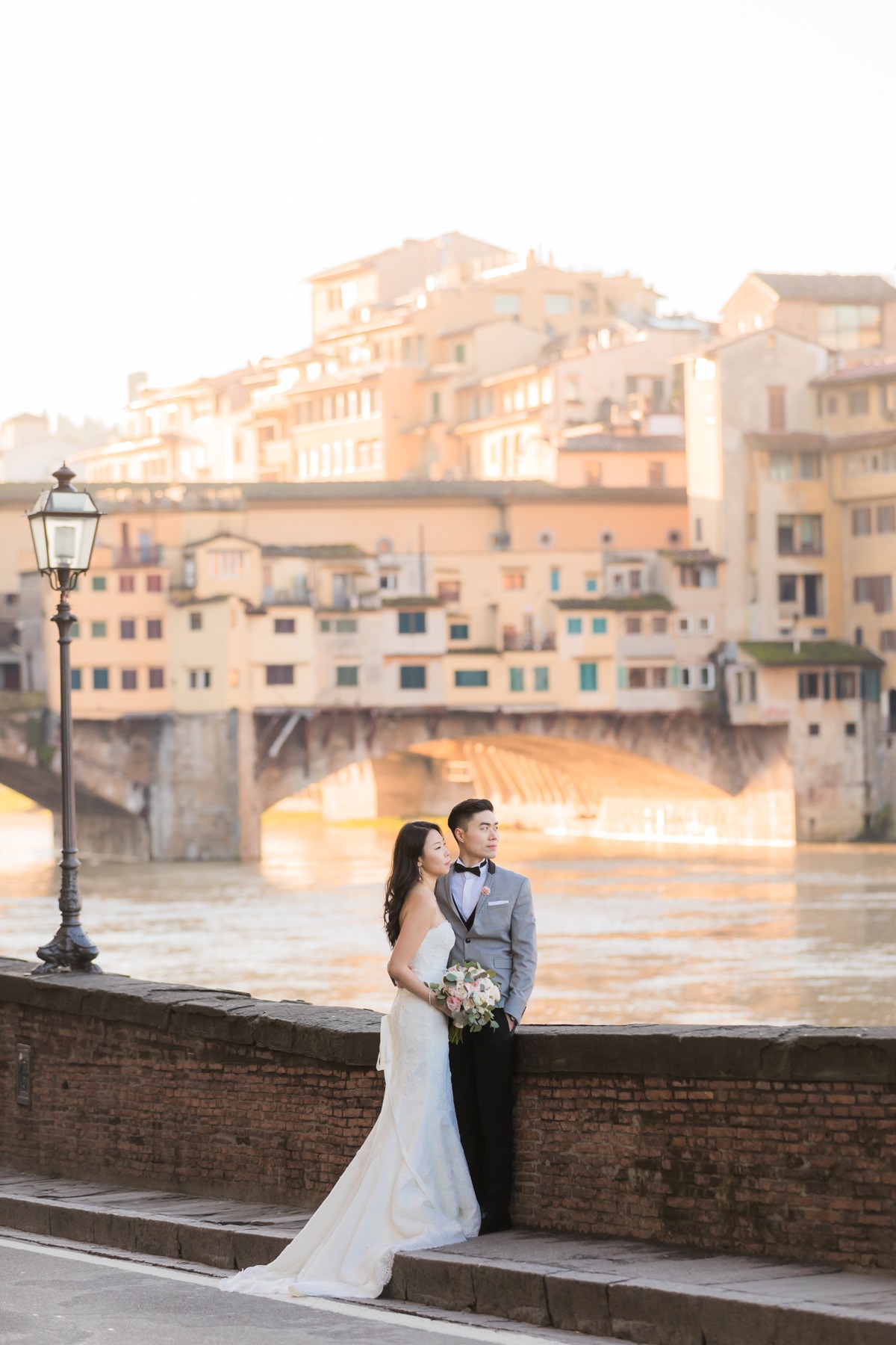 Newlyweds pose beside a historic bridge in Italy for their wedding