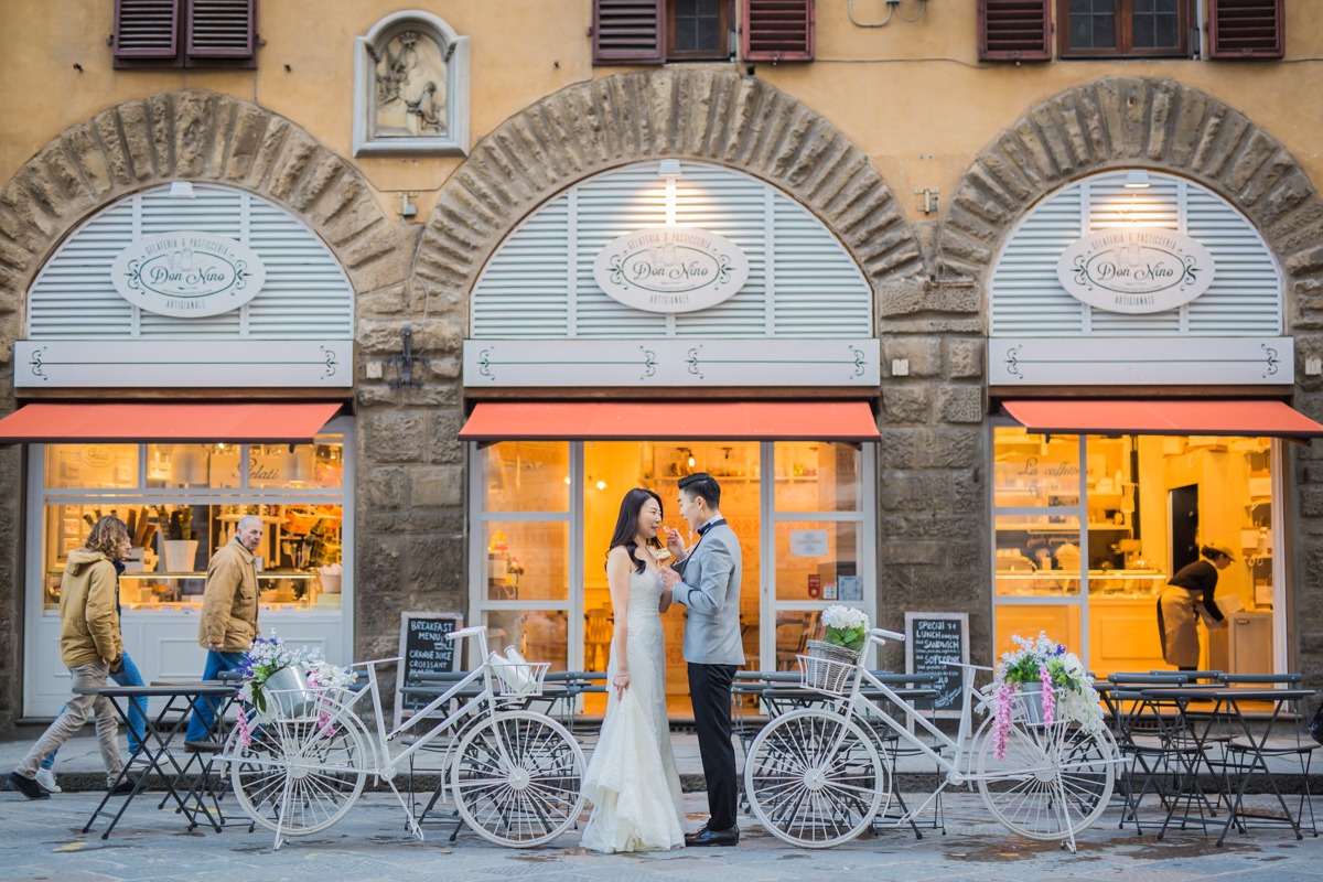 Couple shares a moment in front of a bakery with floral bikes