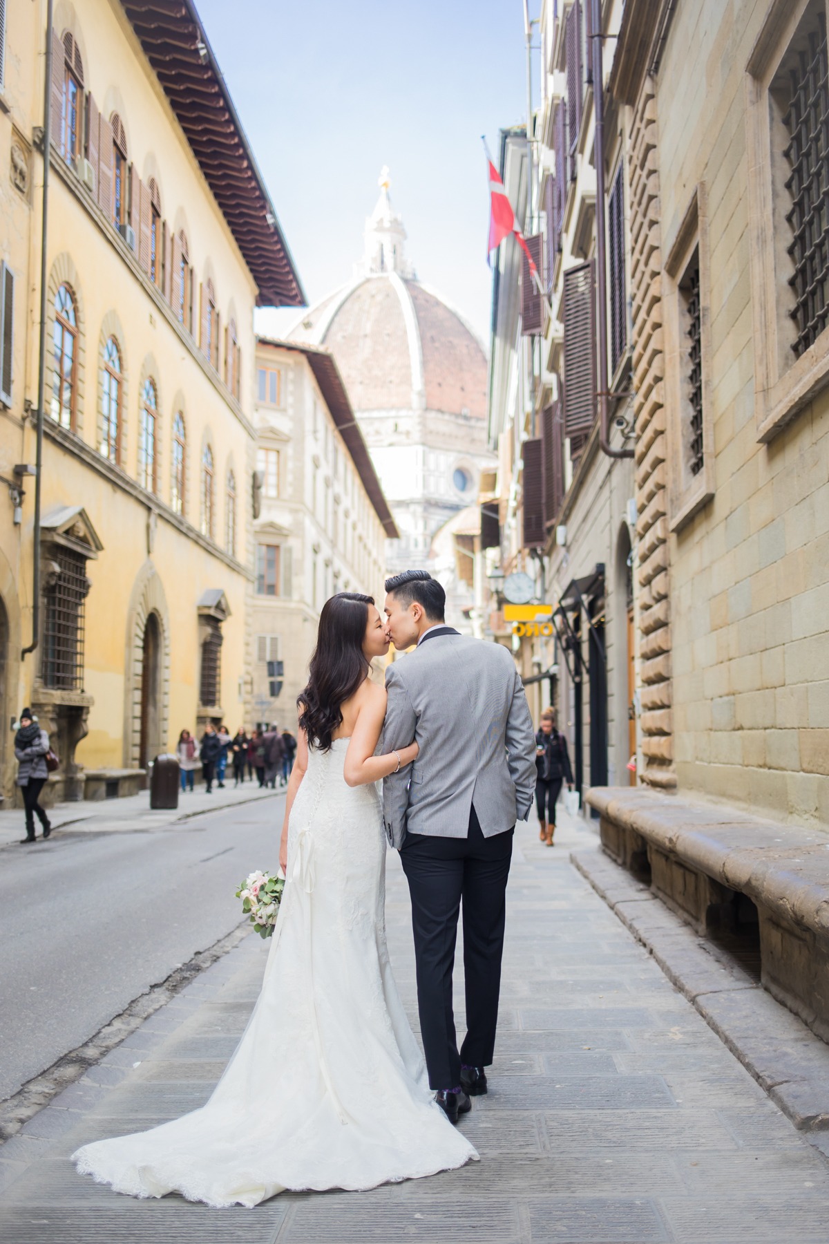 Newlyweds share a kiss while walking through an Italian city street