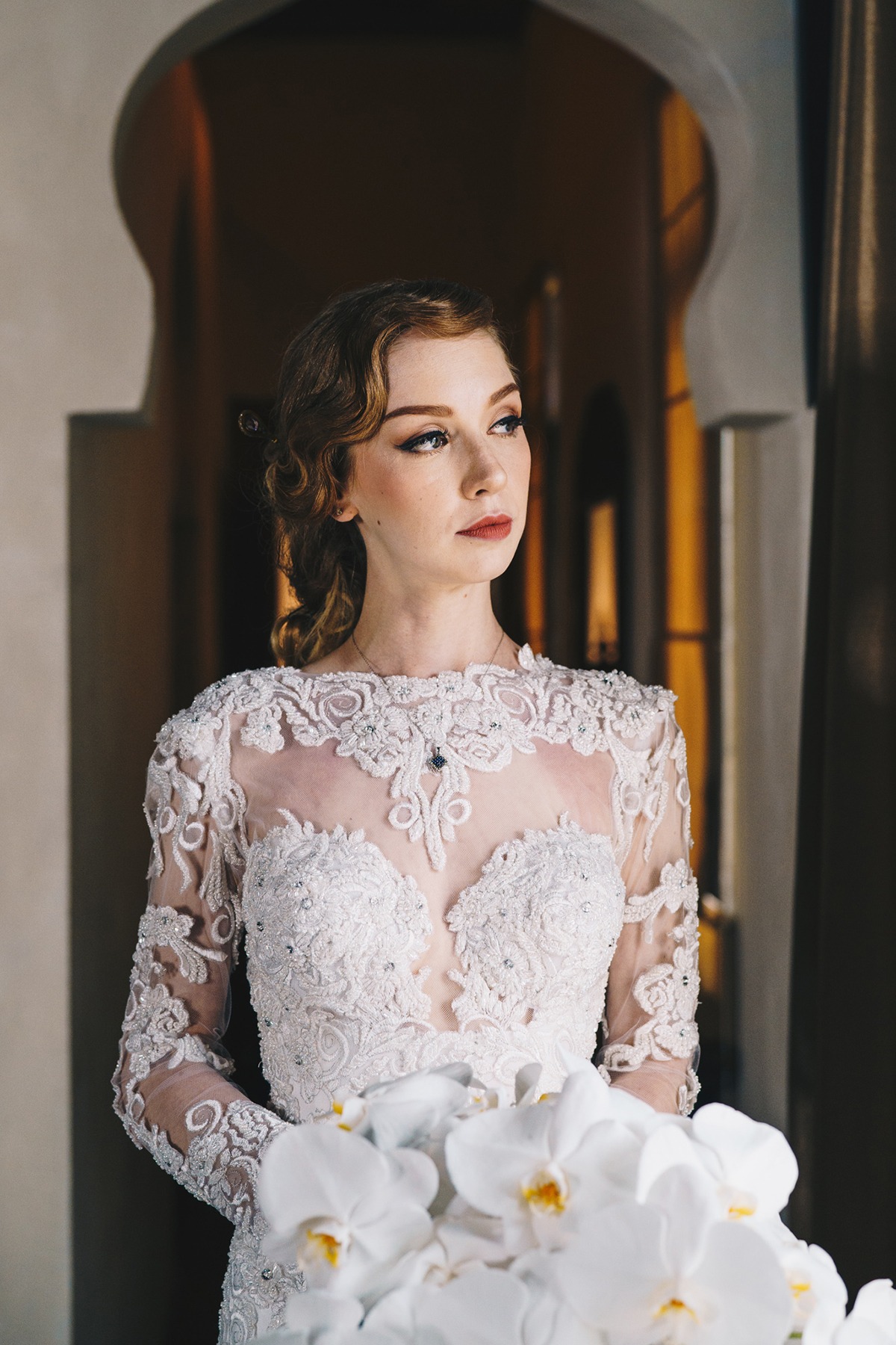 Beautiful bride in a lace wedding dress holding white flowers