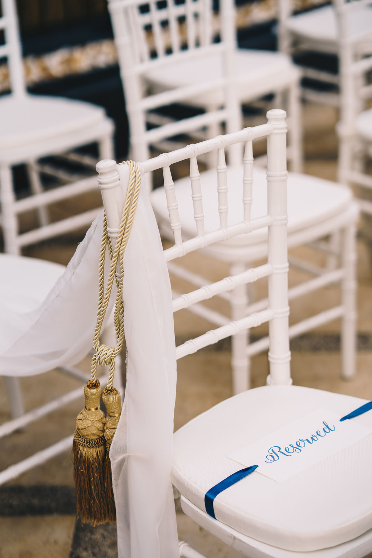 Wedding chairs reserved with blue ribbons and decor