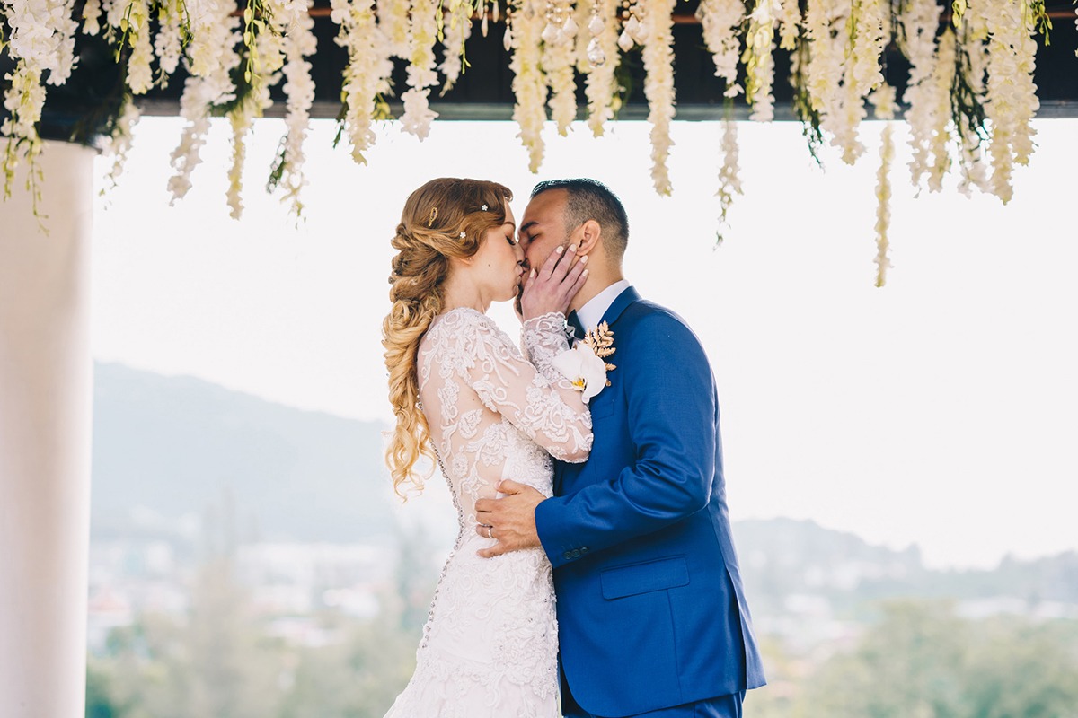 Newlyweds sharing a tender kiss under a floral wedding arbor