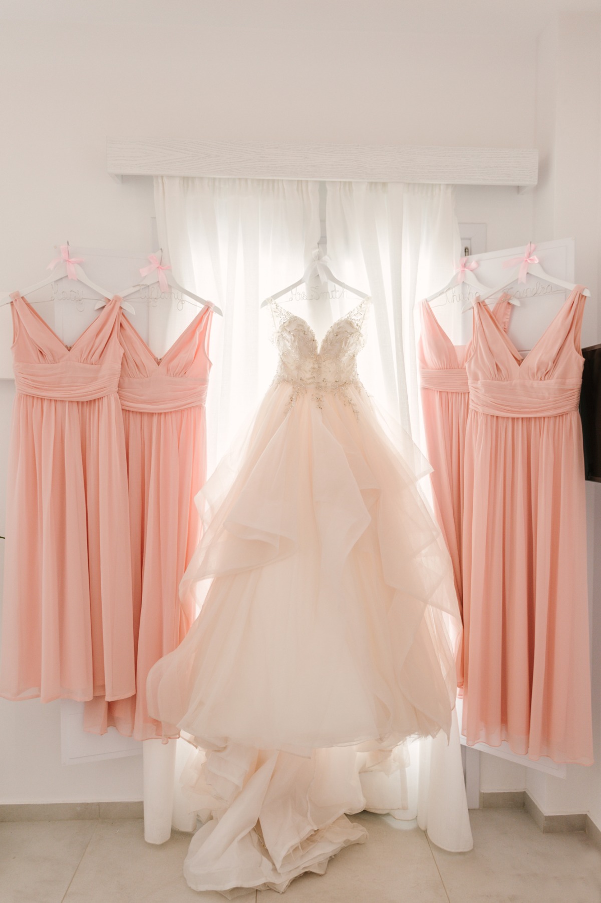 Peach bridesmaid dresses and a wedding gown hang ready