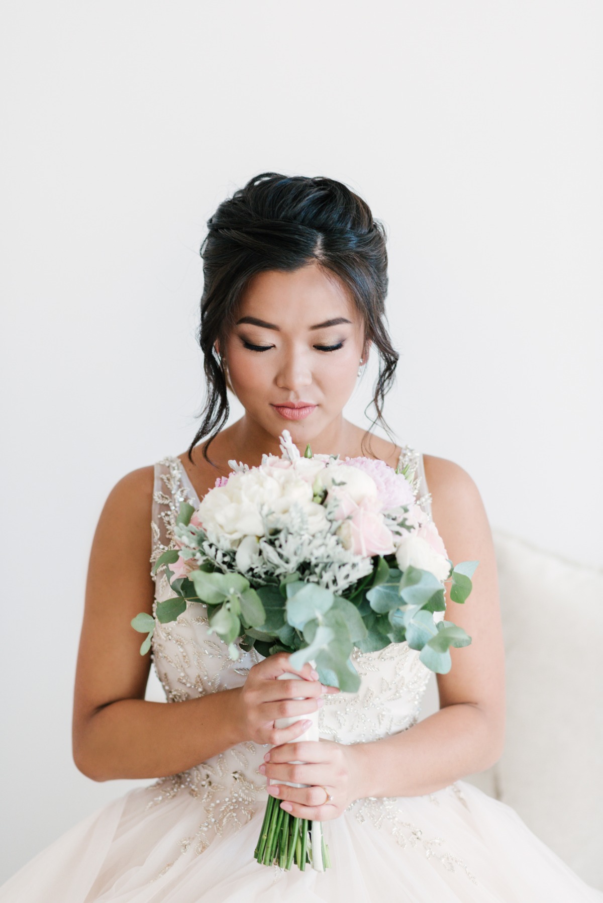 Asian bride holds a beautiful white floral bouquet