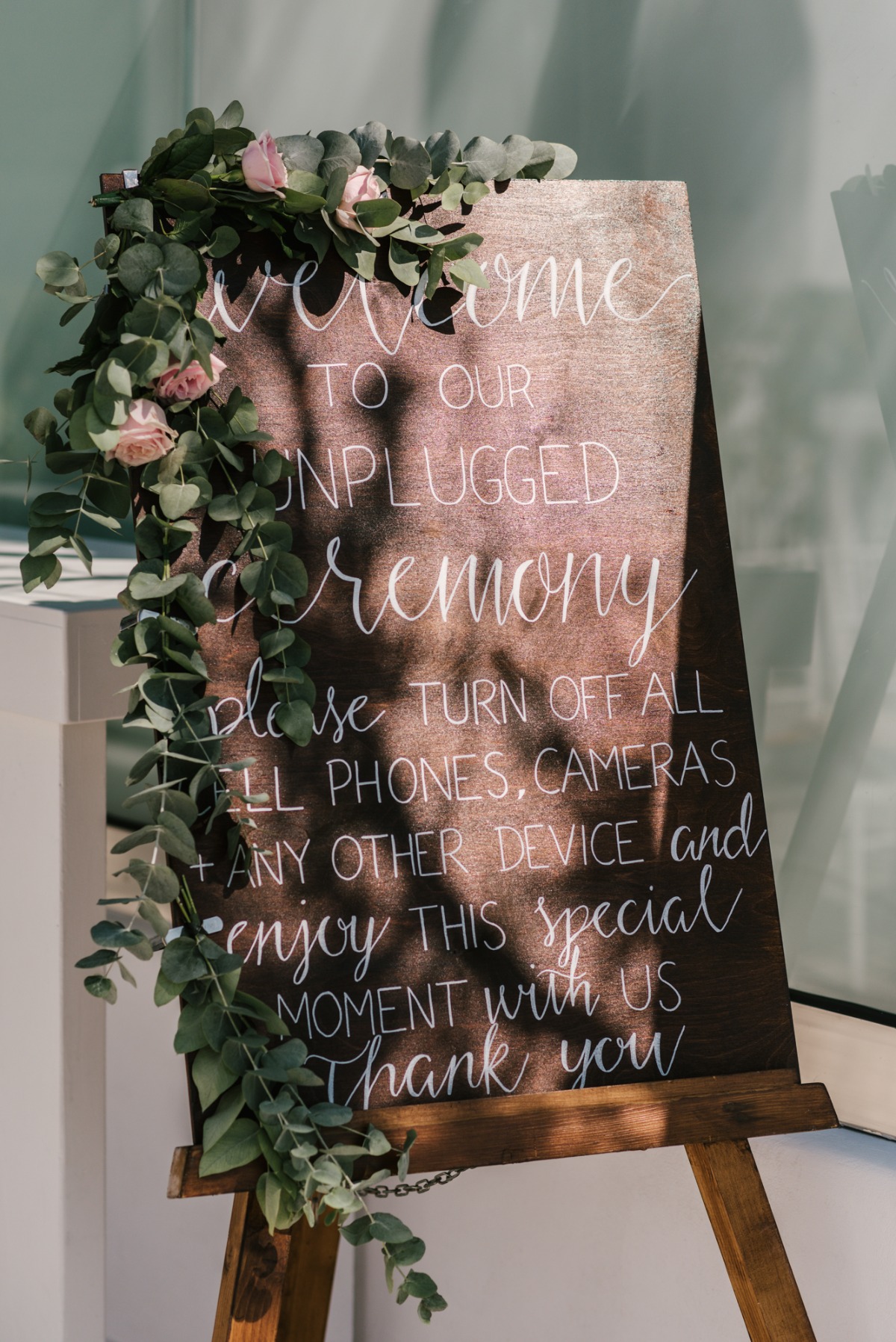 Unplugged ceremony sign decorated with eucalyptus leaves