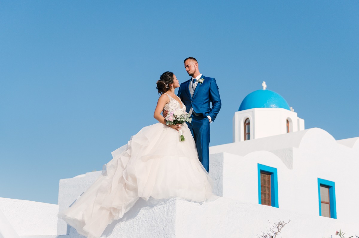Romantic wedding couple posing on a white building with blue sky