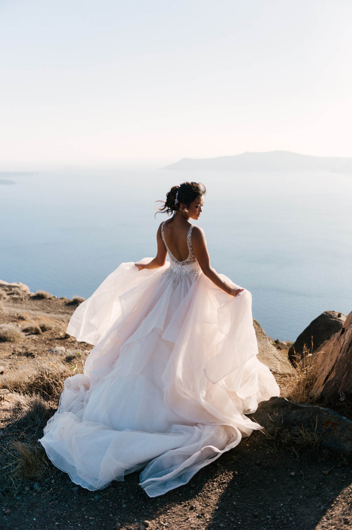 Bride in a beautiful wedding dress stands by the sea
