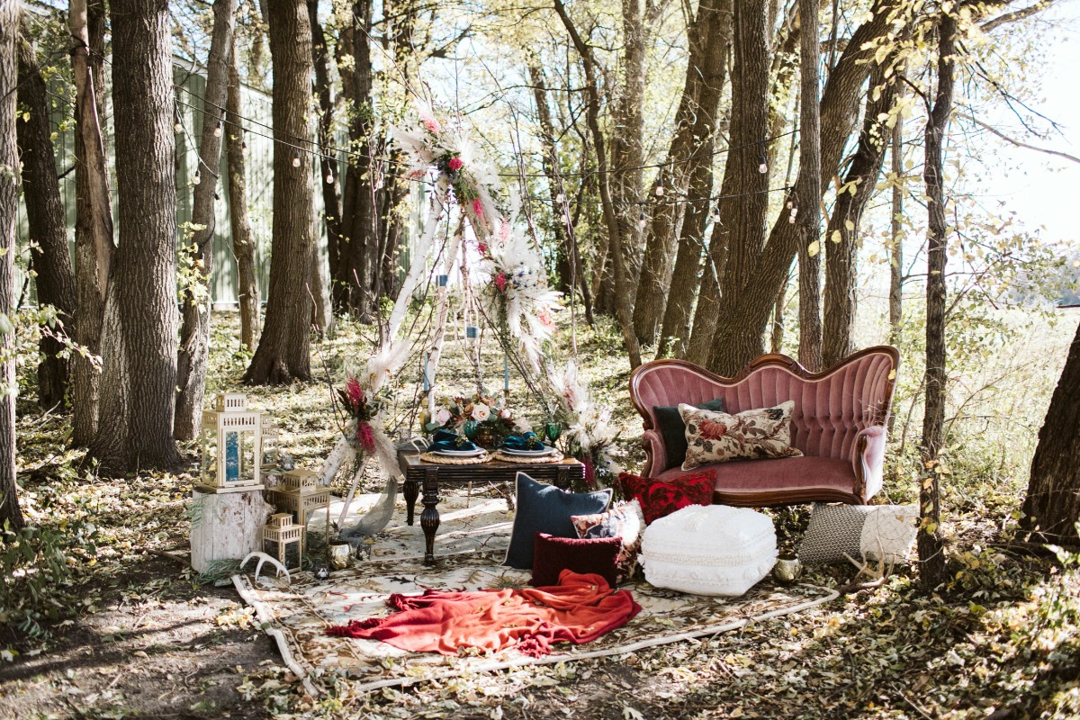 Boho picnic setup with teepee and pink couch in woods