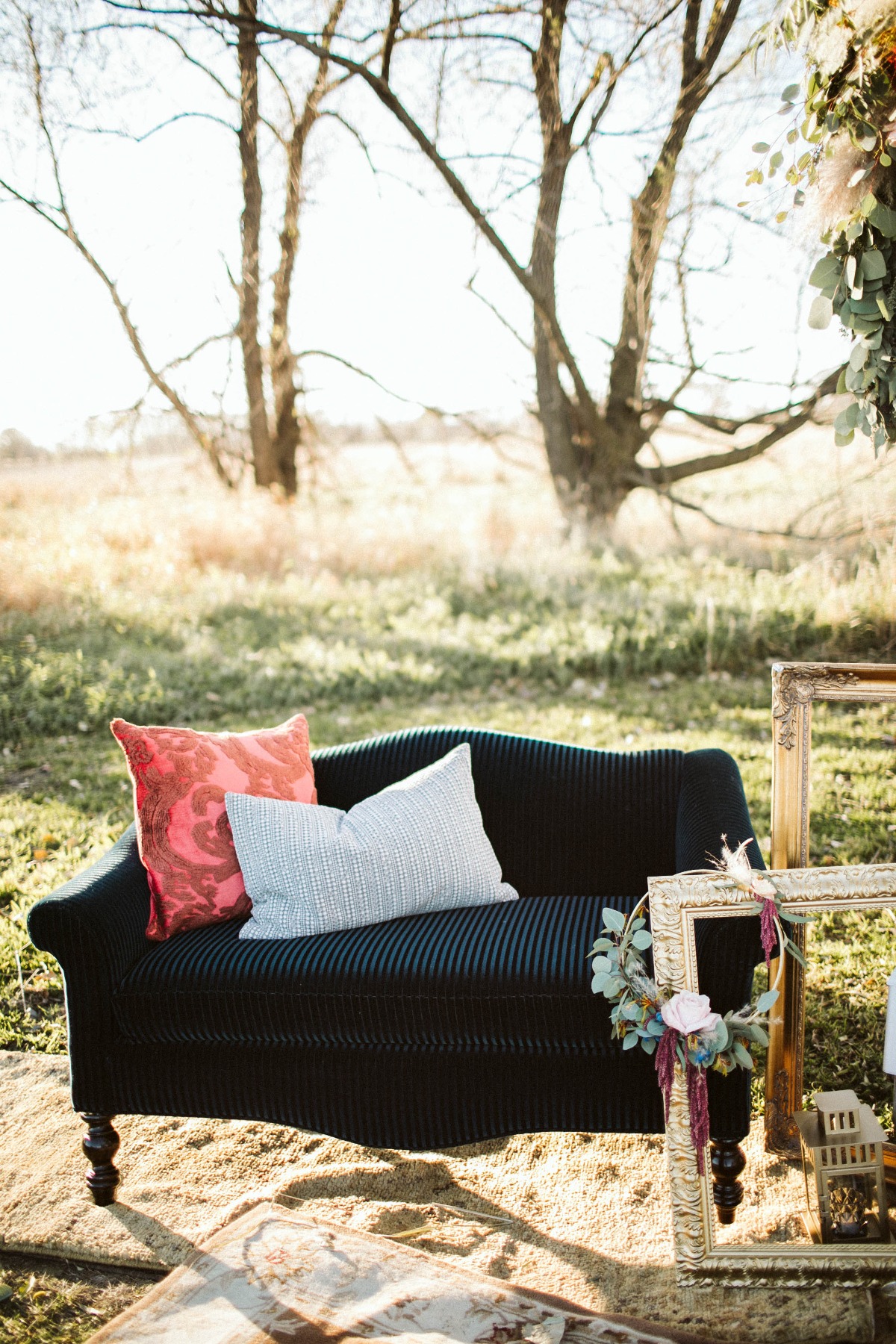 Outdoor setup of black sofa with pillows and frames