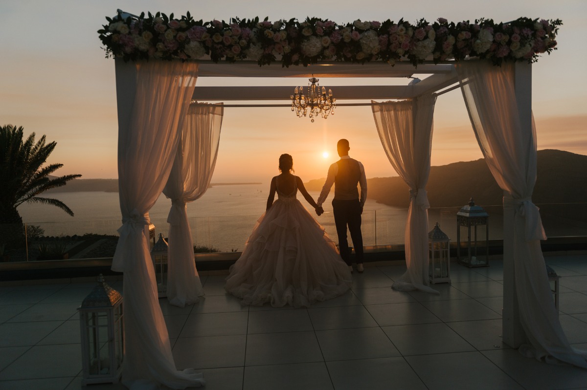 Couple holding hands at sunset on a wedding arch, romantic vibe