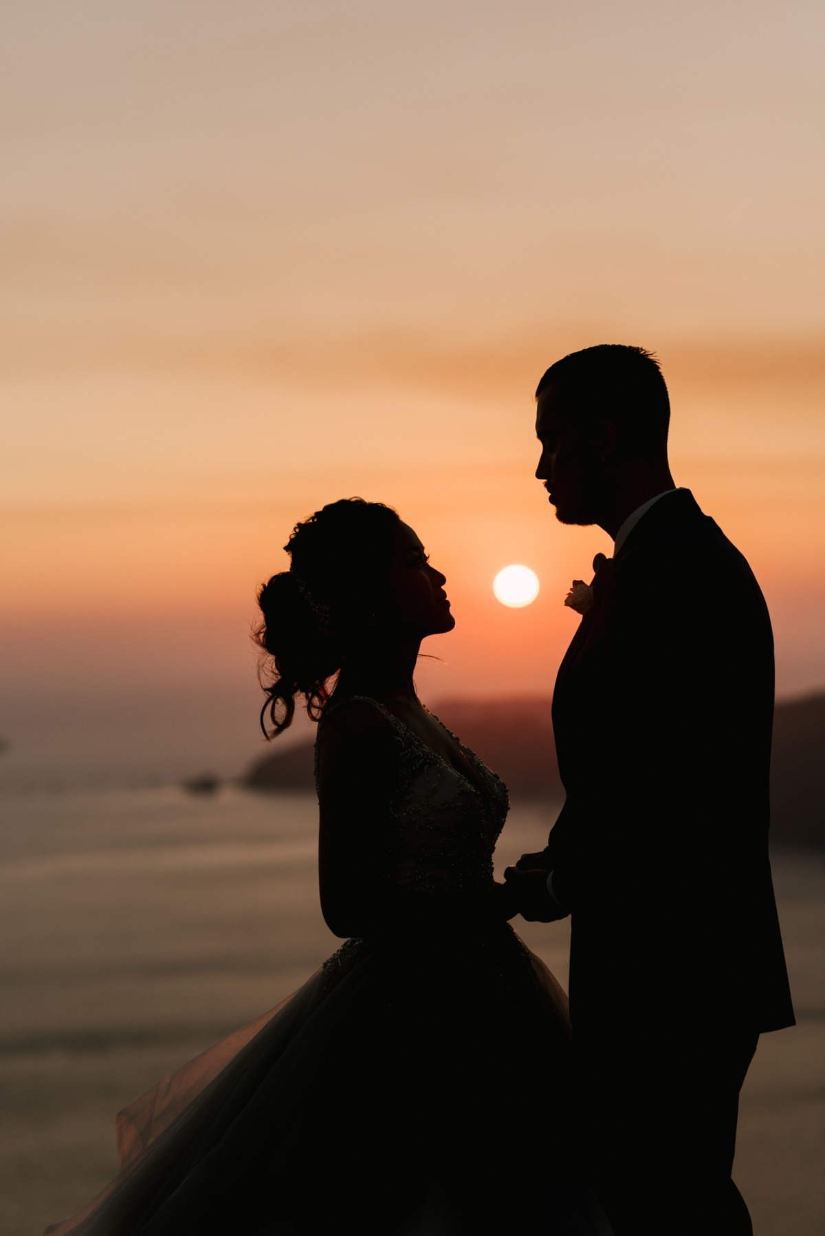 Silhouetted wedding couple gazing at each other during sunset