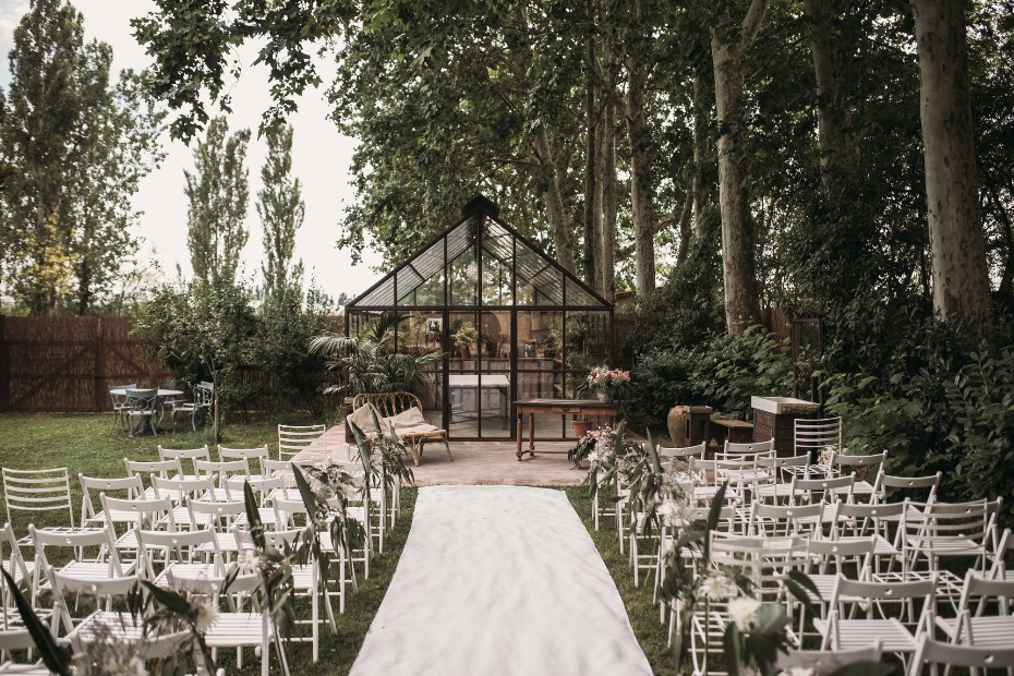 Outdoor wedding ceremony setup with greenery and white chairs