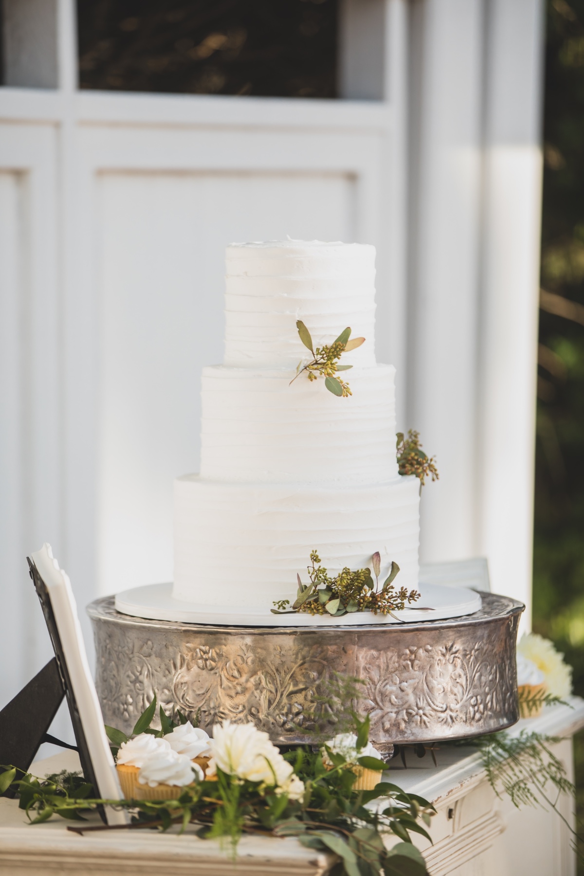 Simple buttercream wedding cake with seeded eucalyptus