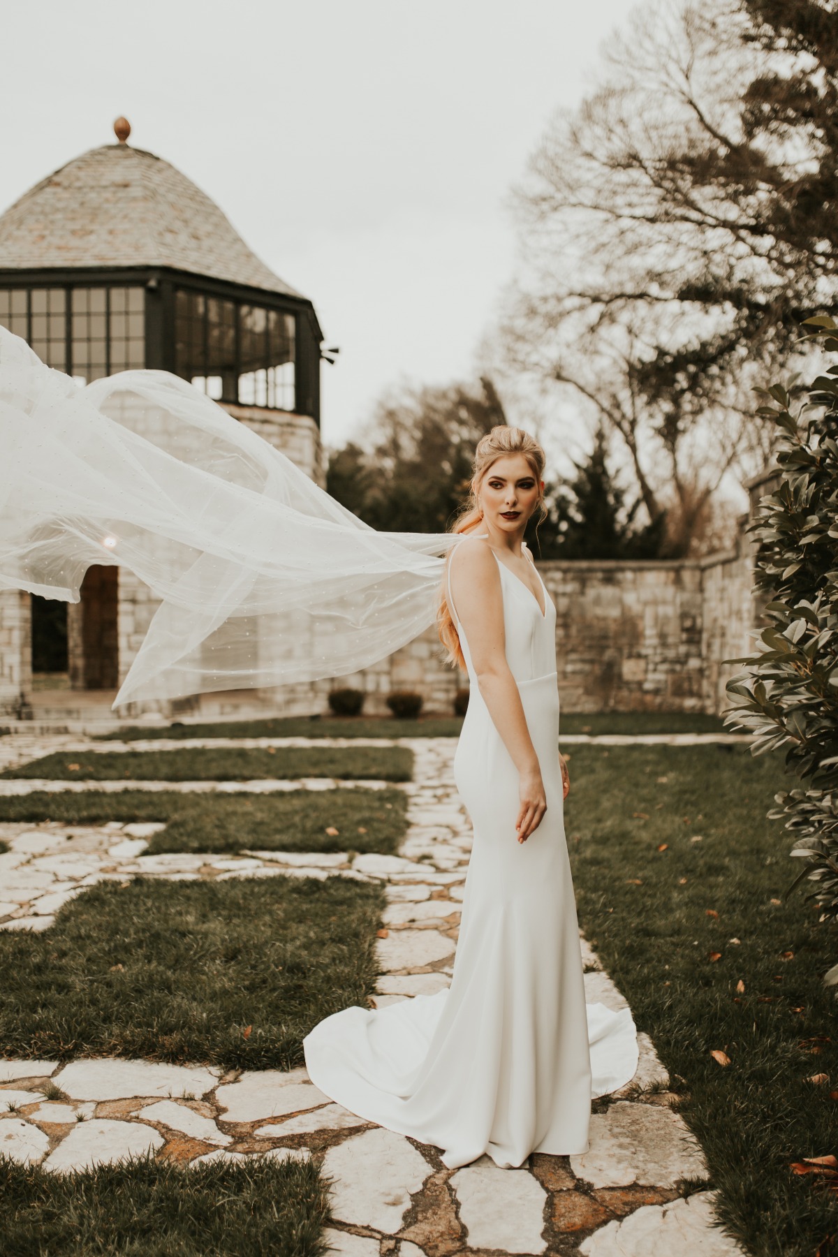 Elegant bride with flowing veil in outdoor garden setting