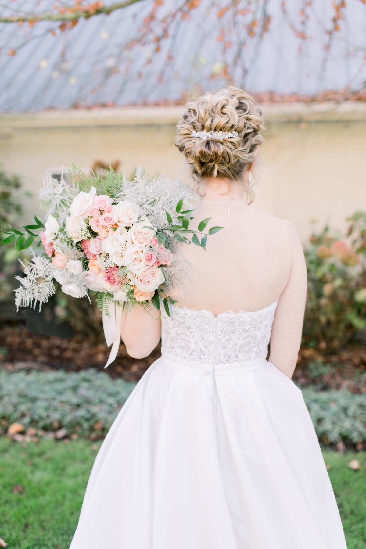 Elegant bride back view holding bouquet and updo hairstyle