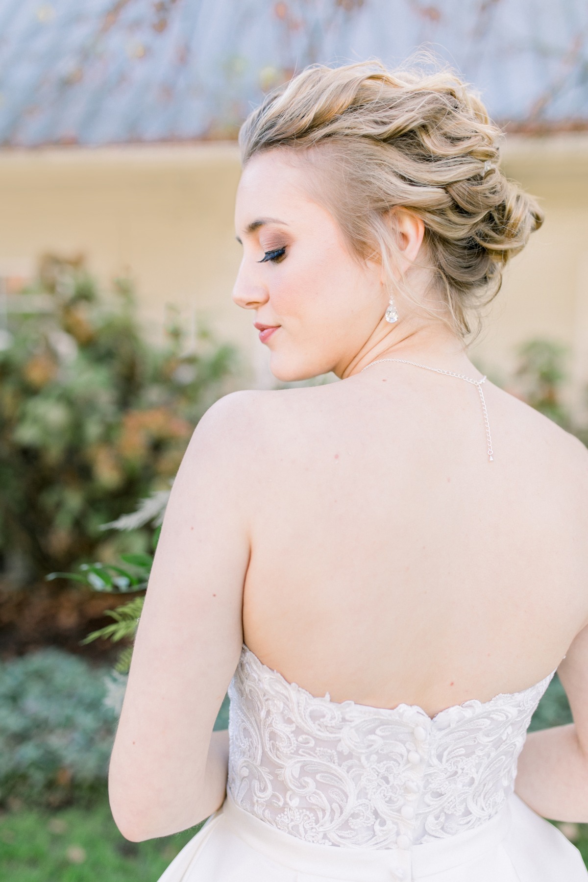 Elegant blonde bride showcases lace dress back hairstyle