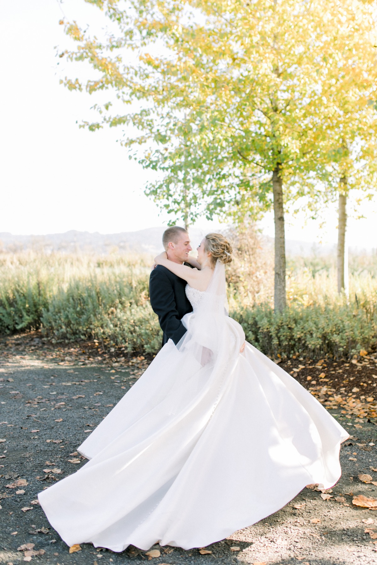 Loving wedding couple embrace outdoors under yellow trees