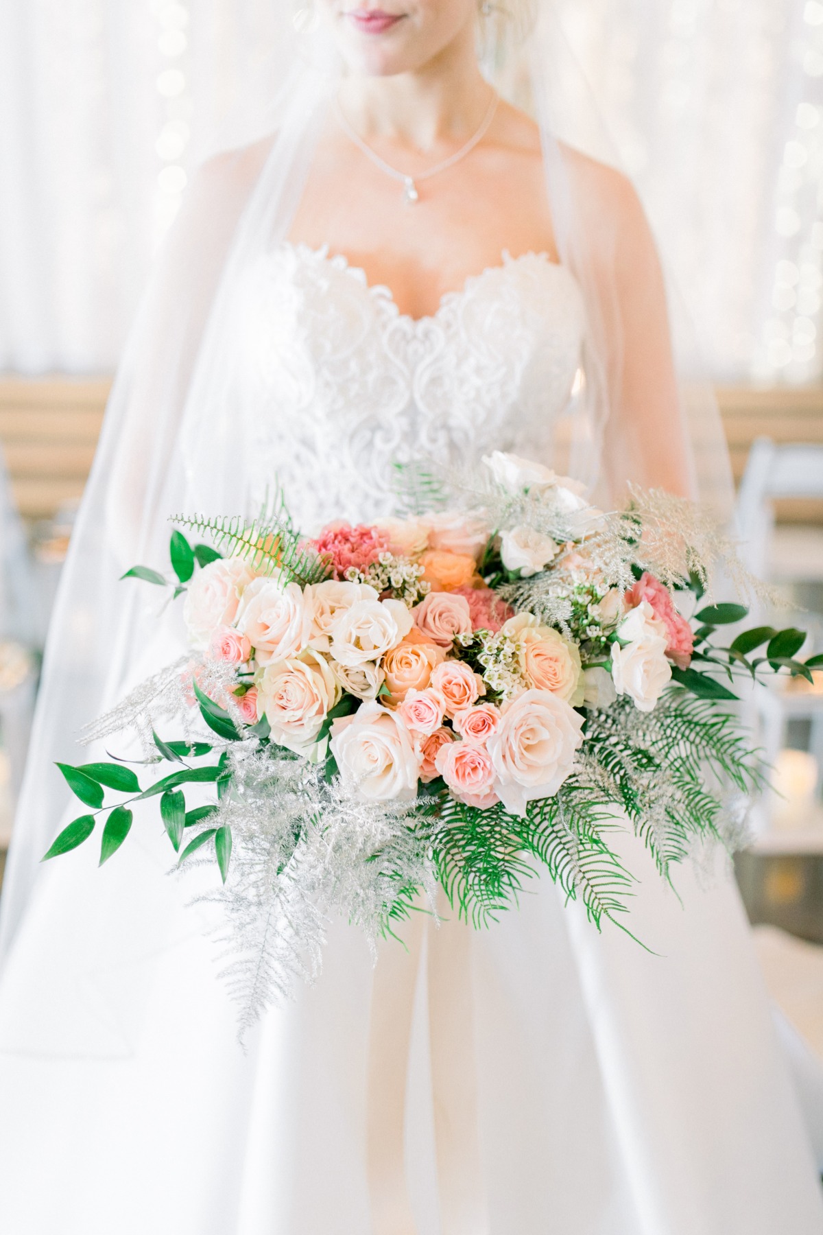 Elegant bride holding pink white rose bouquet at wedding