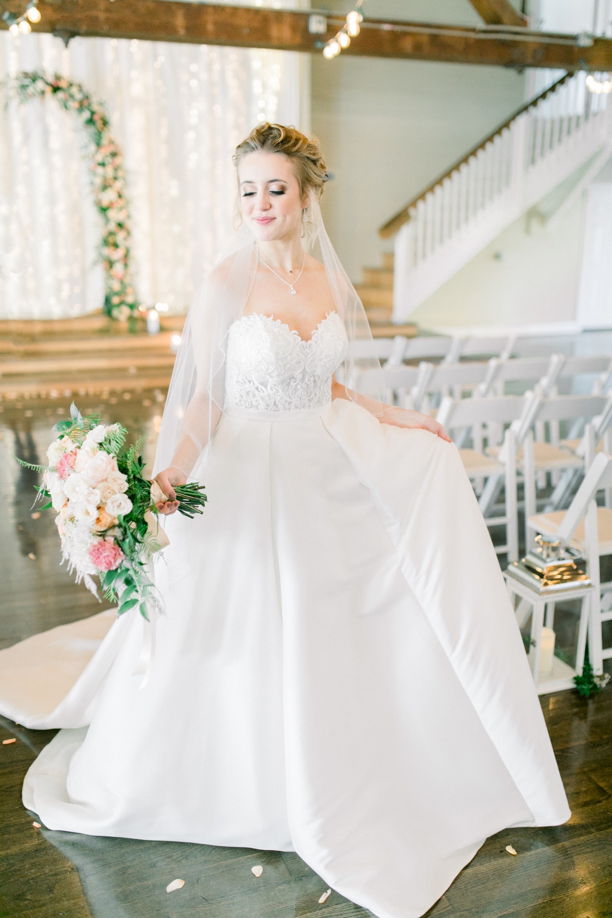 Smiling bride in white dress holds wedding bouquet