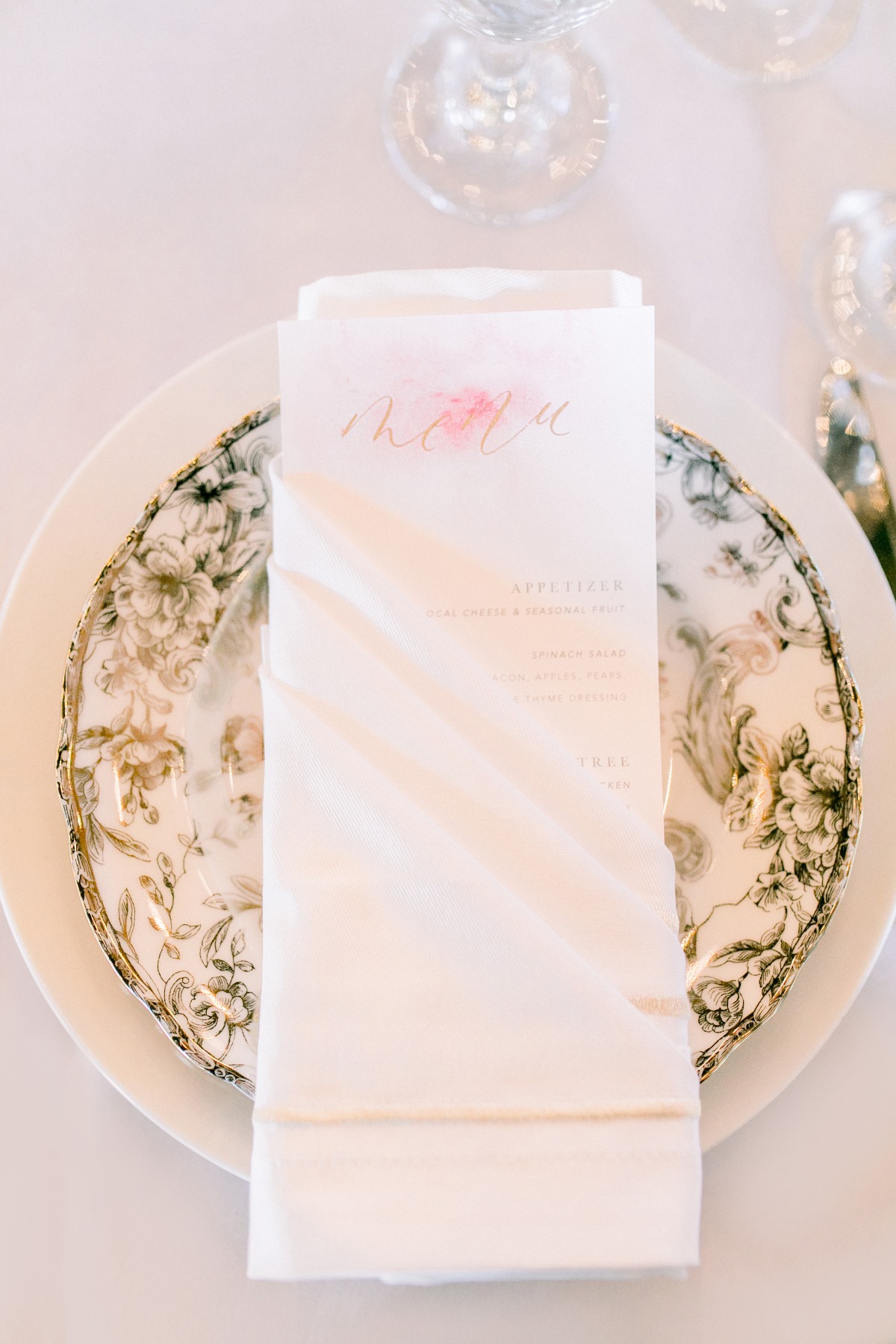 Elegant wedding menu on a floral plate with fine dining setup
