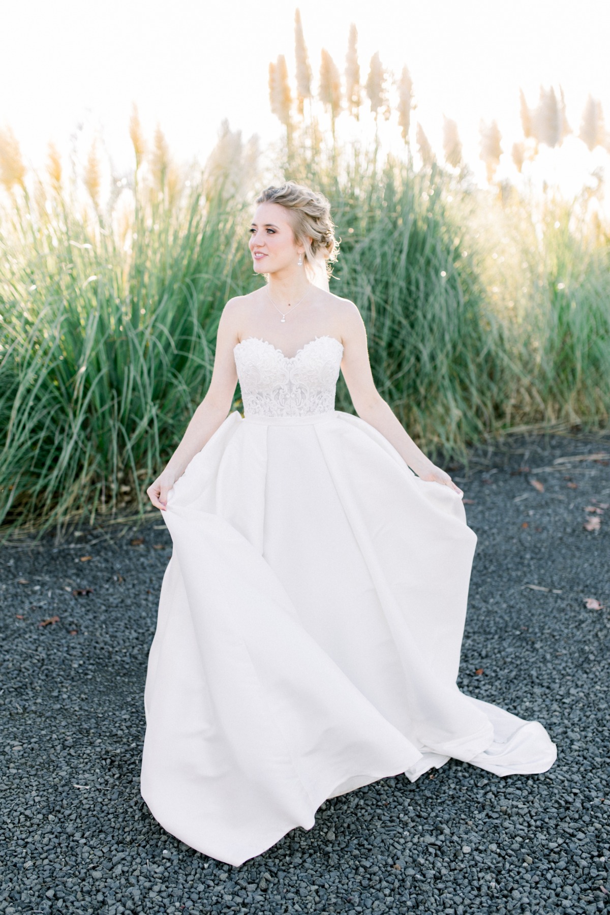 Happy bride holds white gown outdoor wedding venue
