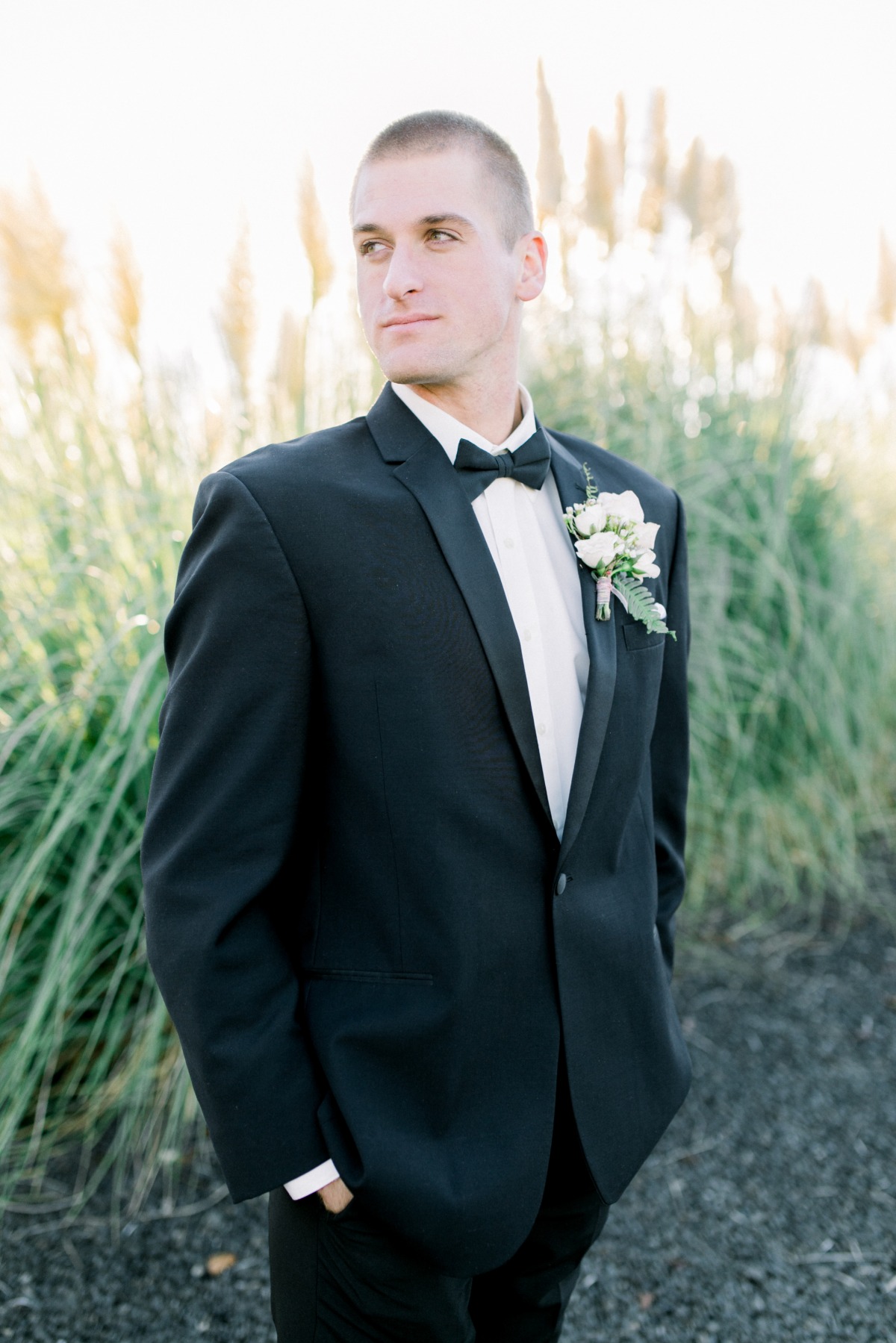Groom in black tuxedo and bow tie outdoor portrait