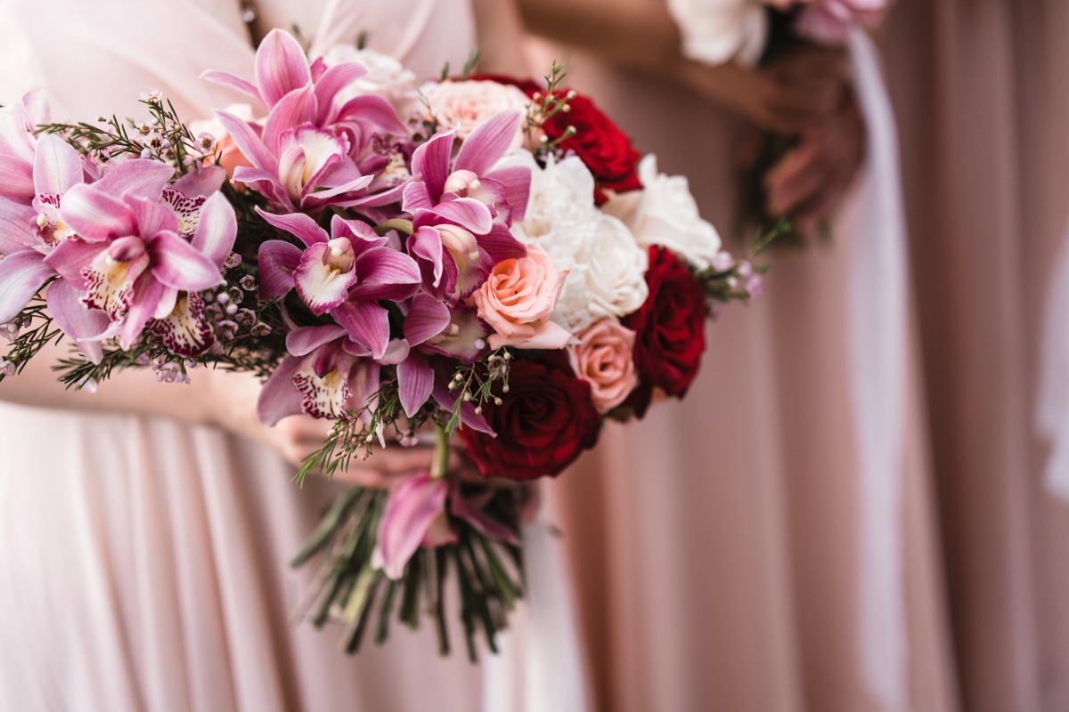 Bridesmaid holds lush bouquet of orchids and roses