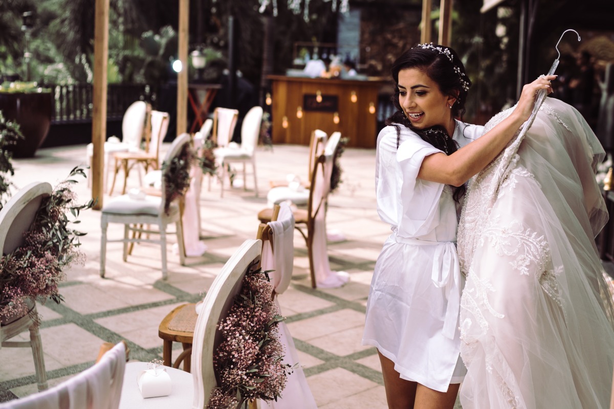 Bride holding wedding dress at outdoor ceremony site