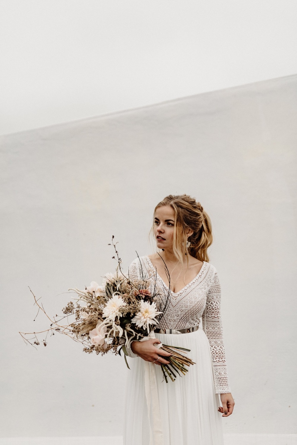 Beautiful bride holding a bouquet of flowers in a white dress