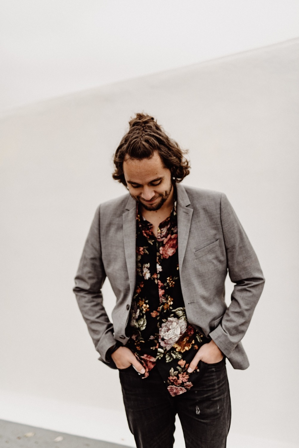 Man with floral shirt and jacket looking down in a casual pose