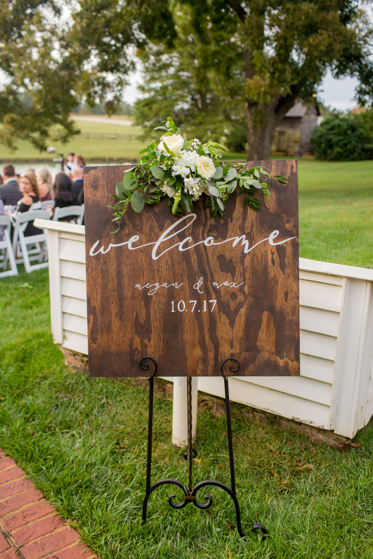 Wooden welcome sign with flowers at outdoor wedding
