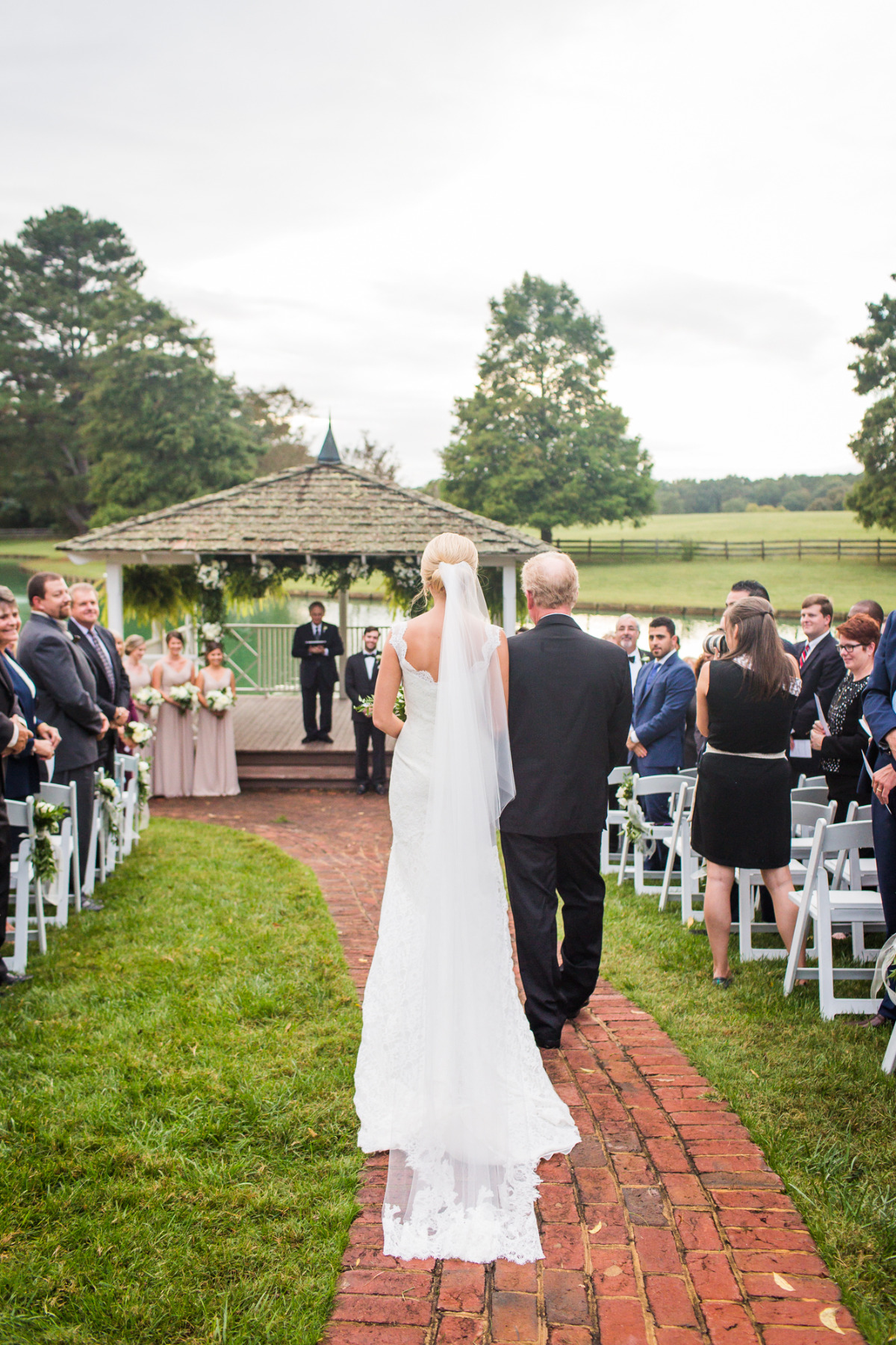 Bride walks down aisle with her father to outdoor wedding