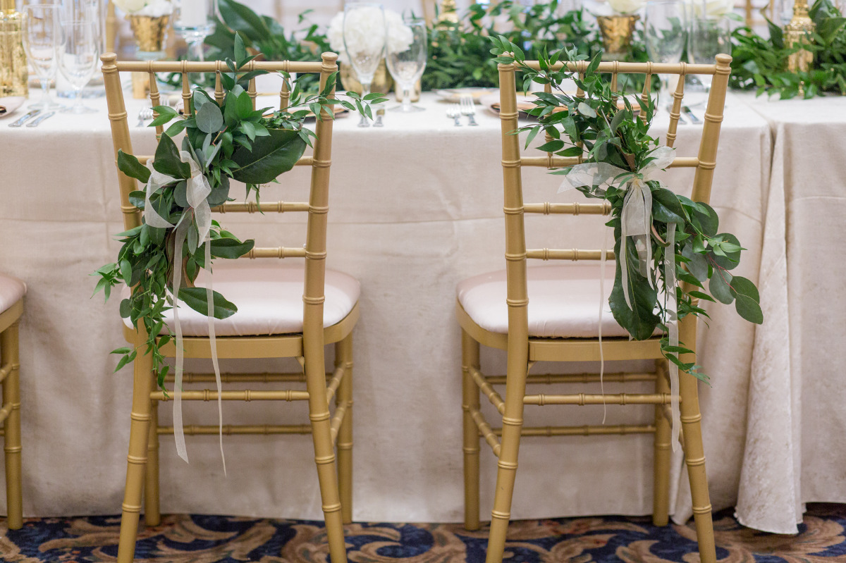 Gold chiavari chairs with greenery at elegant wedding