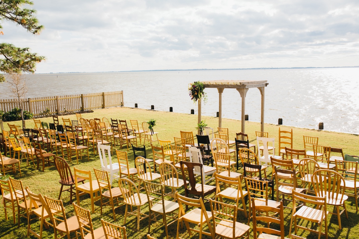 Rustic waterfront ceremony with mismatched chairs