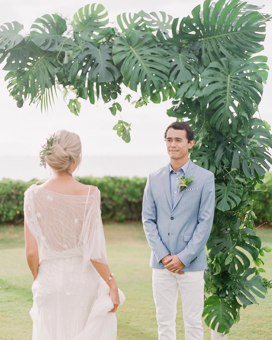 Bride and groom exchange vows under tropical leaves