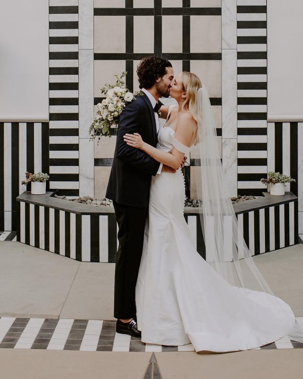 Newlyweds share a kiss at their stylish wedding day