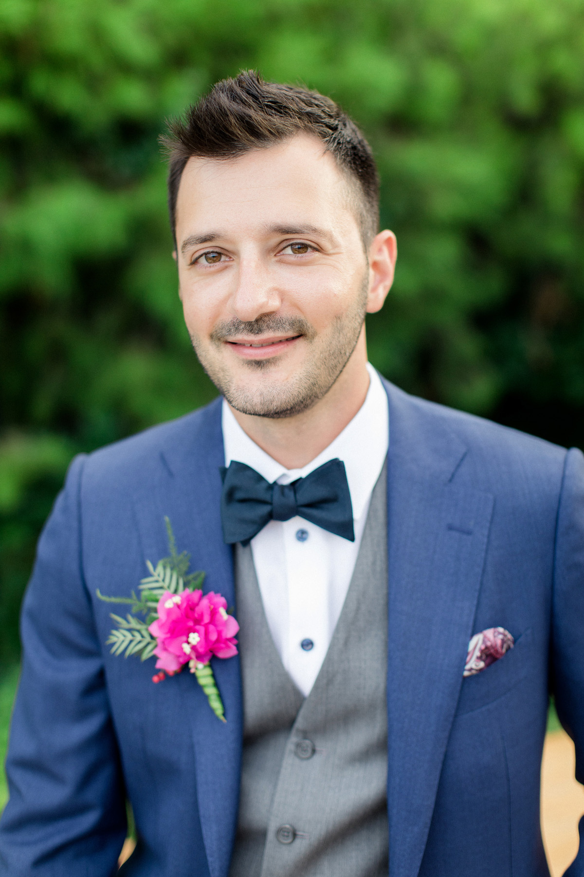 groom in glue suit with grey vest and pink boutonniere
