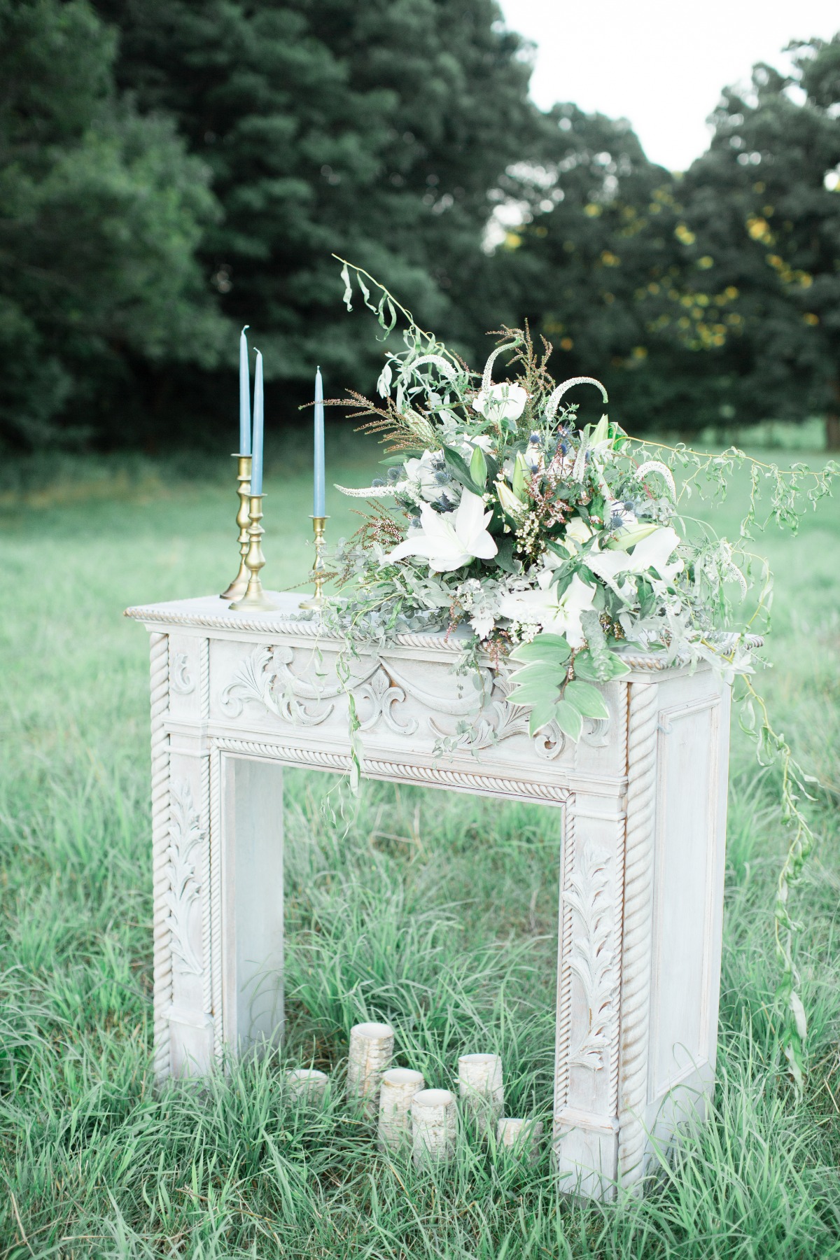 Elegant fireplace decorated with candles and floral arrangement in a field