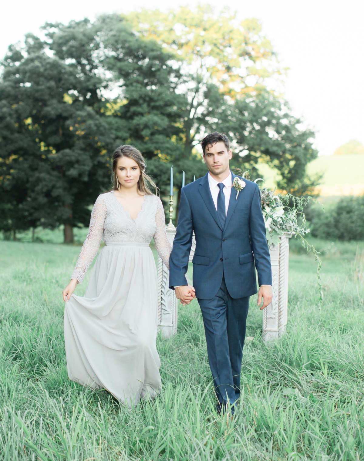 Newlyweds walking in a field, holding hands, happily celebrating