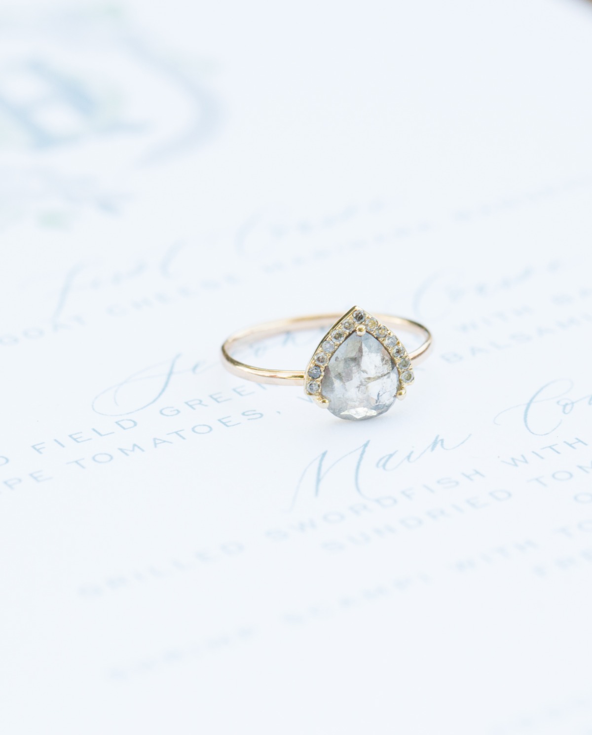 Elegant pear-shaped diamond ring on a textured, light-blue background
