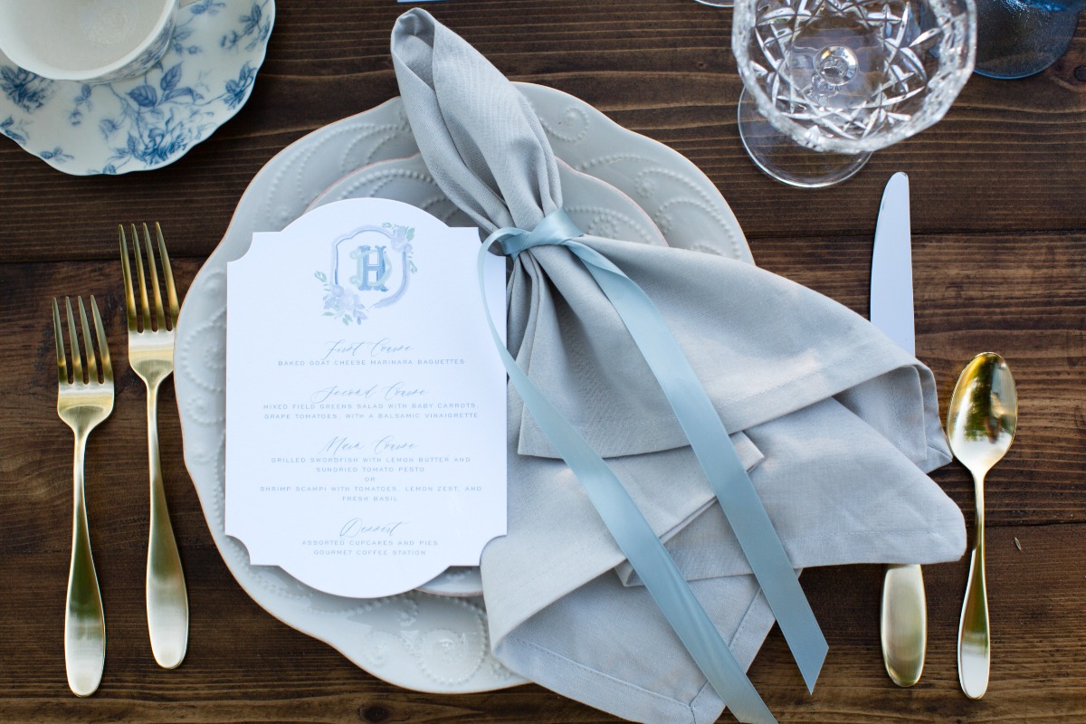 Elegant place setting with menu, golden cutlery and blue accents